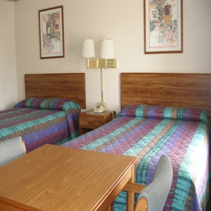 Two double beds, night stand with telephone, wall mounted bedside lights and art, small table and chairs