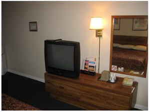 king bed, wooden unit with tv, ice bucket, telephone, wall mounted light and mirror, carpet flooring
