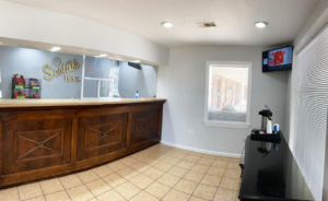Guest check in desk, wall mounted TV, breakfast bar with coffee pot, tiled flooring