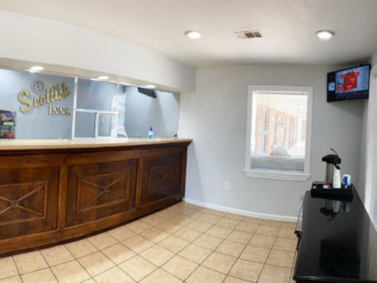 Guest check in desk, wall mounted TV, breakfast bar with coffee pot, tiled flooring