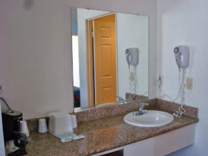 Vanity unit with sink, ice bucket, disposable cups, coffee maker, wall mounted hair dryer, wall mounted mirror