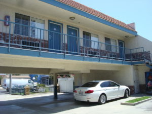 Upper floor of hotel with exterior room entrances and exterior walkway, parking spaces on ground floor