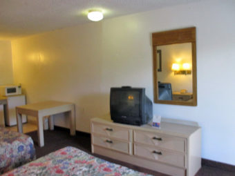 Two double beds, wooden drawer unit with tv, wall mounted mirror, small table, fridge with microwave, carpet flooring