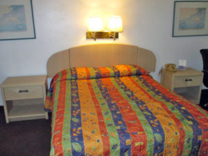 King bed, night stands with telephone. wall mounted bedside lights and art, carpet flooring