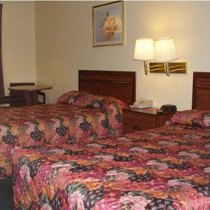 Two double beds, night stand with telephone and clock, wall mounted bedside lights and art, small table with chairs