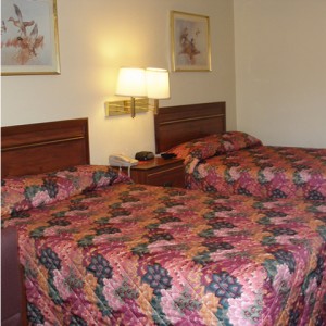 Two double beds, night stand with telephone and clock, wall mounted bedside lights and art