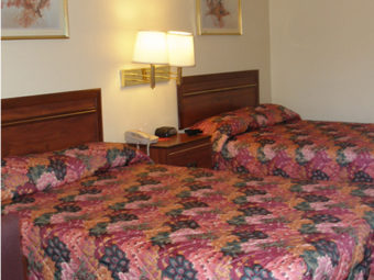 Two double beds, night stand with telephone and clock, wall mounted bedside lights and art