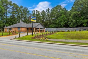 One story building with drive through entrance canopy, brand signage, landscaping with small trees, shrubs and grassy areas.