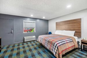 Night stand with telephone, king bed, chair, carpet flooring