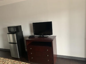 Wooden drawer unit with flat screen tv, fridge with microwave, laminate flooring