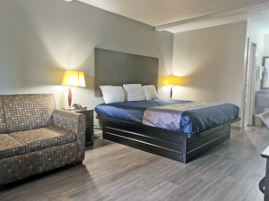 Sofa, king bed, night stands with telephone and bedside lamps, laminate flooring