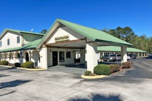 Hotel entrance with drive through canopy, exterior entrances to guest rooms with covered walkway, parking spaces, landscaping with small shrubs