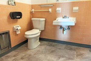 Toilet, grab bar, sink, tiled flooring