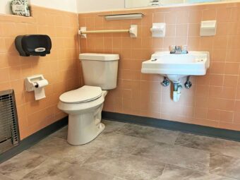 Toilet, grab bar, sink, tiled flooring