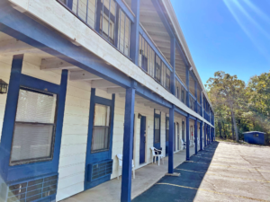 Two story building with exterior room entrances and covered walkwats, parking spaces