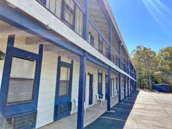 Two story building with exterior room entrances and covered walkwats, parking spaces