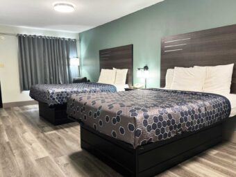 Two queen beds, nightstand with telephone, bedside lights, easy chair, floor lamp, laminate flooring