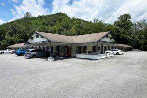One story building with exterior guest room entrances and covered walkway. hotel entrance, parking spaces