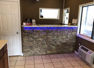 Guest check in area, stone faced front desk with minimal guest information, tiled flooring