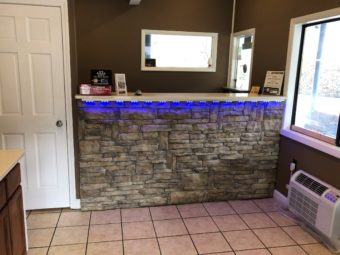 Guest check in area, stone faced front desk with minimal guest information, tiled flooring