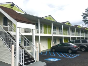 Two story building with external room entrances, walkways and stairs, parking spaces