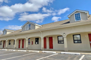 one story building with exterior room entrances and covered walkway, parking spaces