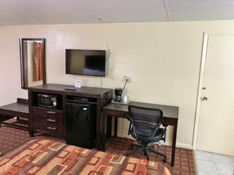 Two queen beds, wall mounted mirror and flat screen tv, wooden unit with microwave and fridge, desk with coffee maker and office chair, carpet flooring