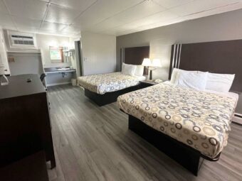 Two queen beds, night stand with bedside lamp and telephone, mirror, shelf and rail with towels, wooden unit, hanging rail with hangers, laminate flooring