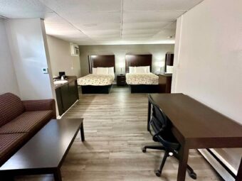 Three queen beds, night stands with bedside lamps and telephone, vanity unit with coffee maker, sofa, coffee table, desk with chair, laminate flooring