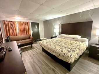 King bed, night stands with bedside lamps and telephone, sofa, coffee table, wooden unit with TV, laminate flooring