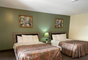 Two queen beds, night stand with lamp and clock, art images, laminate flooring