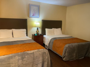 Two queen beds, night stand with lamp and clock, art image, laminate flooring