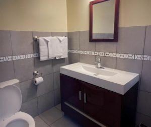 Vanity unit, mirror, towel rail with towels, toilet, tiled flooring