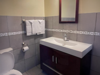 Vanity unit, mirror, towel rail with towels, toilet, tiled flooring