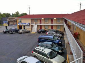 Two story building with external room entrances, brand signage,walkways and stairs, parking spaces