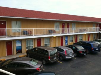 Two story building with external room entrances, walkways and stairs, parking spaces