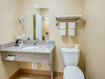 Vanity unit with coffee maker, hairdryer, mirror, toilet, towel shelf and rail with towels, tiled flooring