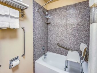 Shower tub with shower chair, grab rails, shower curtain, twoel rails and shelf with towels