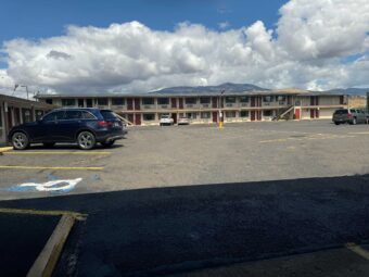 Two story building with exterior guest entrances, covered walkways and stairs, parking spaces
