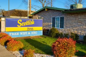 Hotel entrance brand signage, landscaping with grass, shrubs and decorative stones