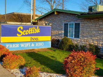 Hotel entrance brand signage, landscaping with grass, shrubs and decorative stones