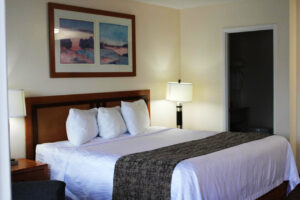 Queen bed, night stands with bedside lamps, art image, doorway to bathroom