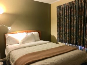 Queen bed, corner floor lamp and carpet flooring