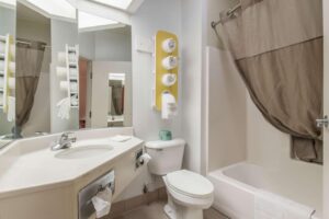 Vanity unit, mirror, stand with towels, shower tub with shower curtain and bath mat, toilet
