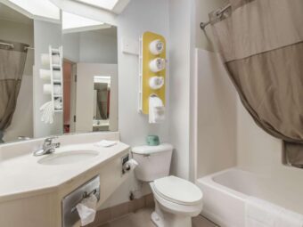 Vanity unit, mirror, stand with towels, shower tub with shower curtain and bath mat, toilet