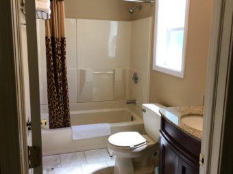 Shower tub with shower curtain, vanity unit, toilet, tiled flooring