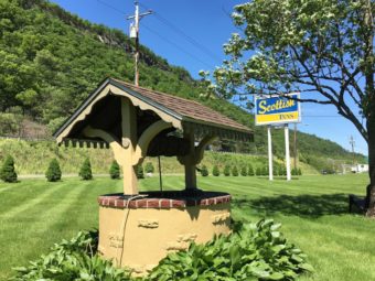 Wishing well, brand signage, trees, grassy area