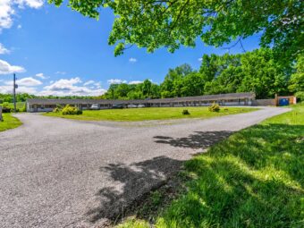 One story building, exterior guest room entrances, parking spaces, grassy areas and trees