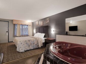 King bed, night stands, wall bedside lights,wooden drawer unit, art images, spa tub with tiled surround, carpet flooring