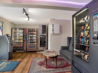 Vending machines with snacks and drinks, ATM, sofa, coffee table, laminate flooring and rugs